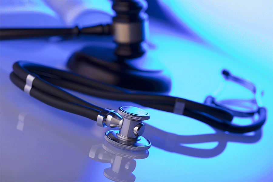 Gavel and stethoscope on desk with dramatic lighting